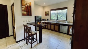 A modern kitchen with a dining area, featuring a large window, a refrigerator, a microwave, and a sink. - 2 BR Condo Centrally Located in Playas del Coco (Playas del Coco)