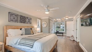 Une chambre avec un grand lit, un ventilateur de plafond et une vue sur l’extérieur.