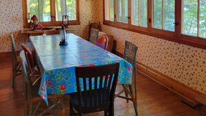 A dining room with a large table, wooden chairs, and a window with a view of trees. - Classic Northwoods Cabin Experience Awaits You (Lac du Flambeau)