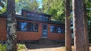 A log cabin with a stone pathway leading to the entrance, surrounded by trees. - Classic Northwoods Cabin Experience Awaits You (Lac du Flambeau)