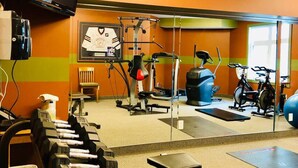 Un gimnasio con equipo de ejercicio, un espejo y una televisión.