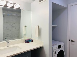 Une salle de bain équipée d’un lavabo, d’un miroir, d’un porte-serviettes et d’un lave-linge.