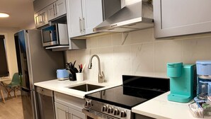 Una cocina moderna con electrodomésticos de acero inoxidable, un lavamanos doble y una cafetera.