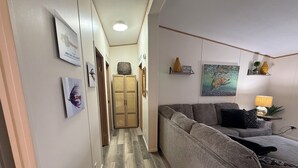 Ein Flur mit einem grauen Sofa, einem gewebten Korb und einem Bild an der Wand.