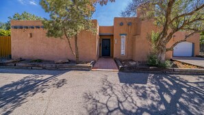 A stucco house with a front entrance, a garage, and a driveway. - Right At Home-Midland Adobe Compound with Pool and Fire Pits and Billiards (Midland)