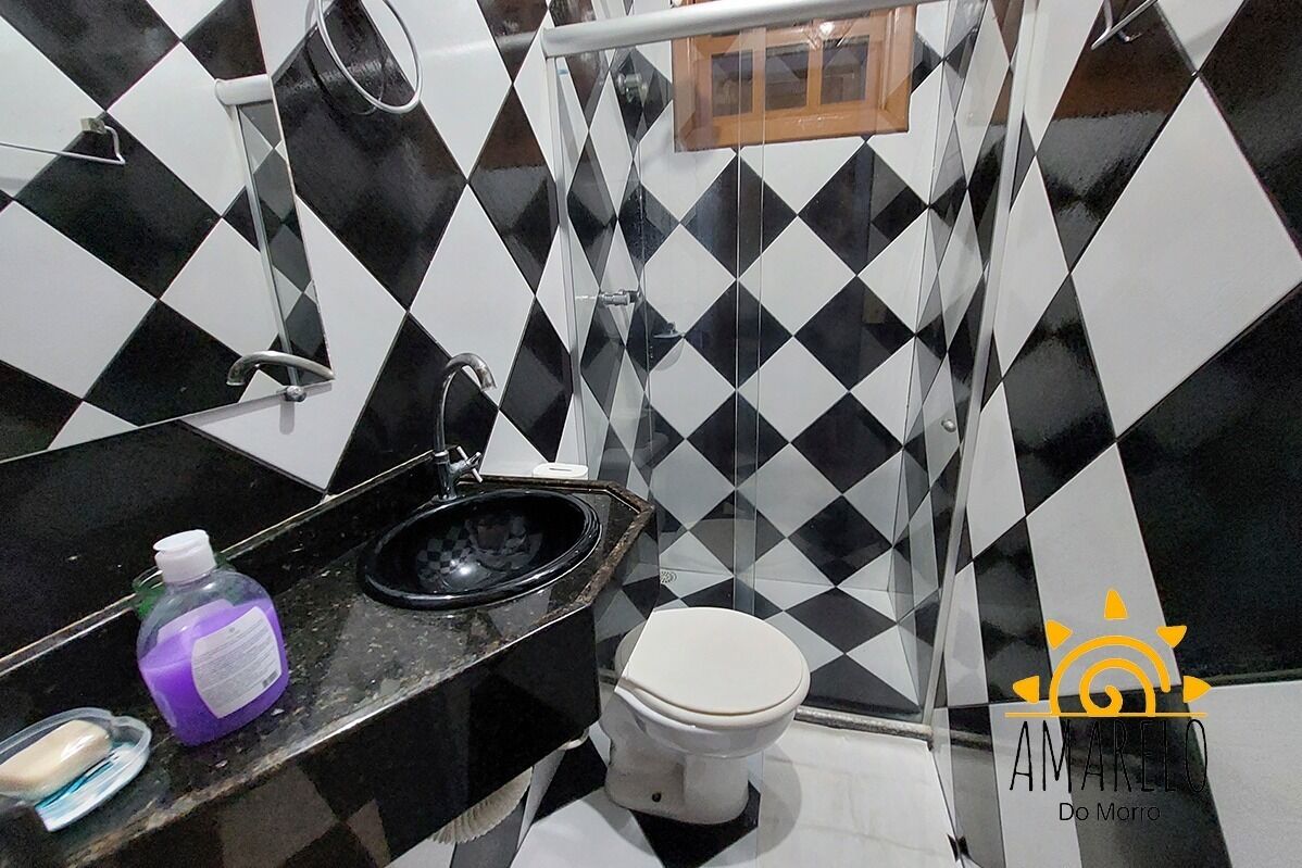 Un bagno con pavimento a scacchi bianco e nero, un water bianco, un lavandino nero e uno spazio doccia.