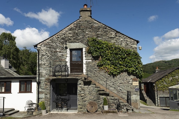 Un bâtiment en pierre avec un toit en pente, une porte et une fenêtre.