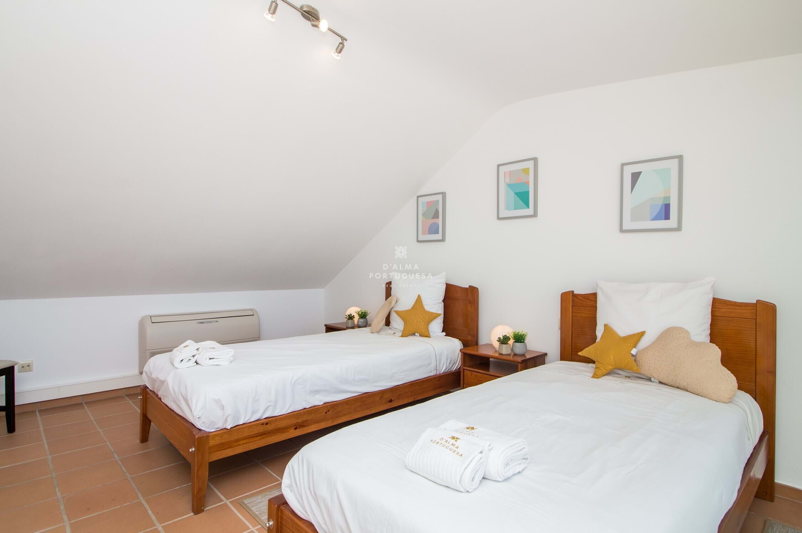 A bedroom with two beds, a ceiling fan, and a small table with a lamp.