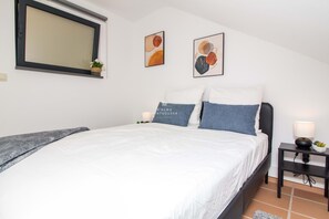 Ein Schlafzimmer mit einem Bett, einem Nachttisch, einer Lampe und zwei Wandbildern.