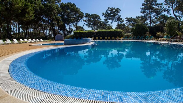 En klarblå pool med solstolar och ett trädäck.