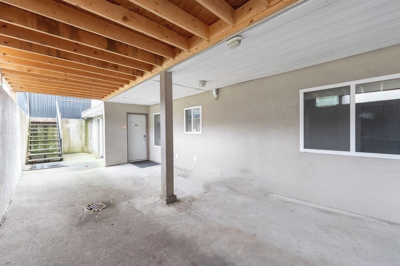 A building with a covered outdoor area, concrete floors, and a door leading to a garage.