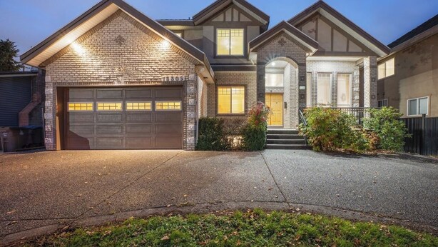 A two-story house with a garage, a front porch, and a brick exterior.