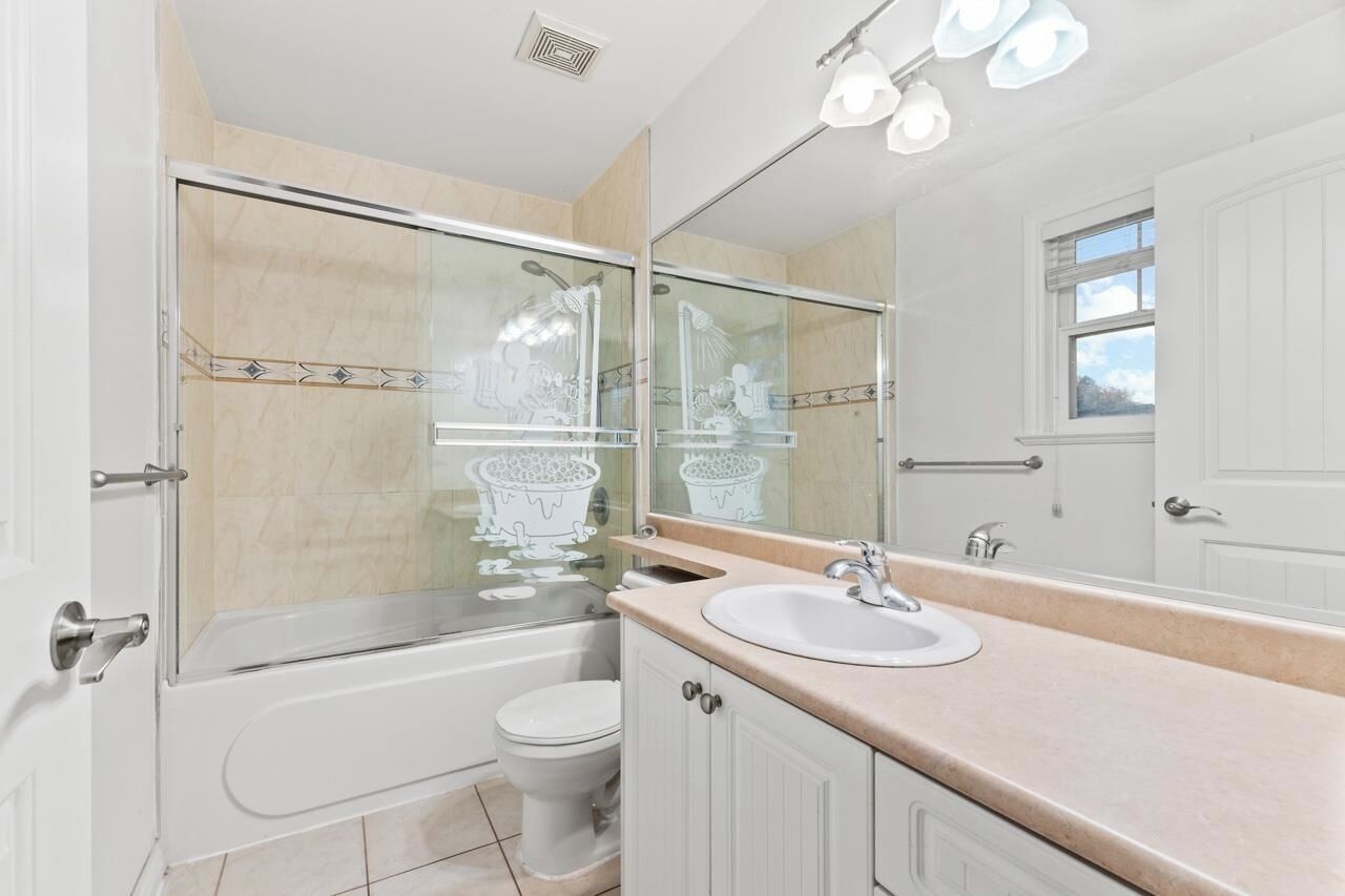 A modern bathroom with a glass-enclosed shower, a bathtub, a toilet, and a sink with a mirror above it.
