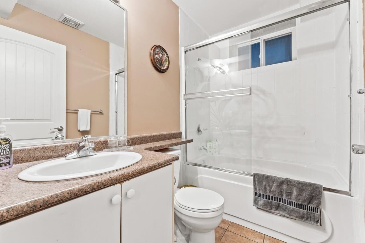 Un bagno con lavandino, specchio, portasci, WC e doccia con pareti in vetro.