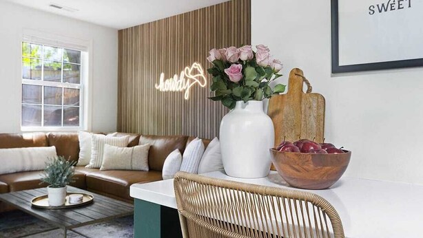 Una sala moderna con un sofá de cuero marrón, una mesa de centro blanca y una silla de mimbre.