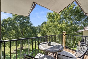 Enjoy a serene view of the lush landscape from this balcony, featuring a table for two and a lantern-style light.