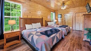 A wooden cabin bedroom with two beds, a ceiling fan, and a large window. - HUGE 7BD Lodge IN TOWN +Pool Table + Views (Gatlinburg)