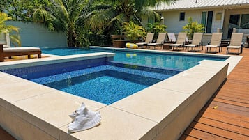 Una piscina rectangular con borde de azulejos, rodeada por una cubierta de madera.