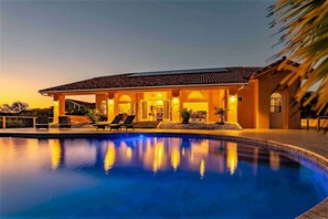 Une maison avec une piscine, un patio couvert et un coin repas.