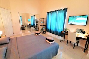 Une chambre d’hôtel équipée d’un lit, d’un bureau, d’une chaise, d’une télévision et d’un grand miroir.