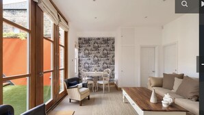A spacious living room with a large window, a dining area, and a cozy seating area. - Exclusive Apartment with terrace, garage, gym in Georgian Residence well located (London)