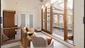 A spacious room with large windows, a wooden staircase, and a view of a brick building outside. - Exclusive Apartment with terrace, garage, gym in Georgian Residence well located (London)