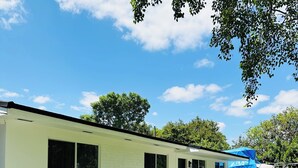 A single-story building with a flat roof, a small porch, and a clear sky.