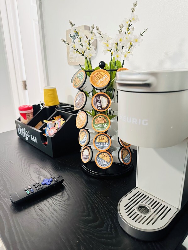 A coffee maker, a remote control, and a tray of cookie jars on a black table. - Peaceful Private Studio with King Bed, Bath & Dining Space in Little Havana 🌴 (Miami)