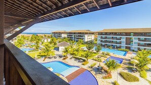 Resort com várias piscinas, palmeiras e um edifício grande com varandas.