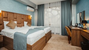 A hotel room with two beds, a wooden desk, a chair, and a large window with curtains. - Alison Hotel Baku (Baku)