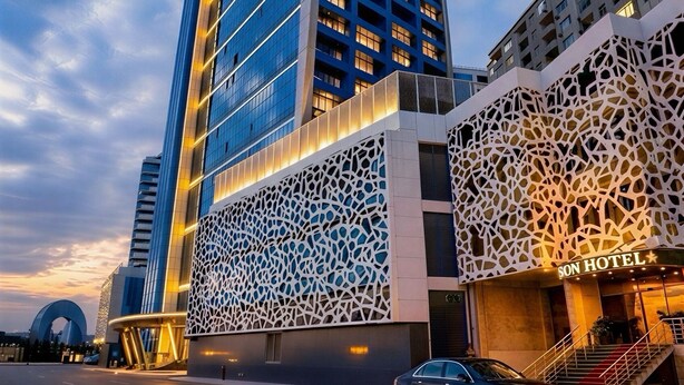 A modern hotel with a distinctive facade, a prominent entrance, and a car parked in front. - Alison Hotel Baku (Baku)