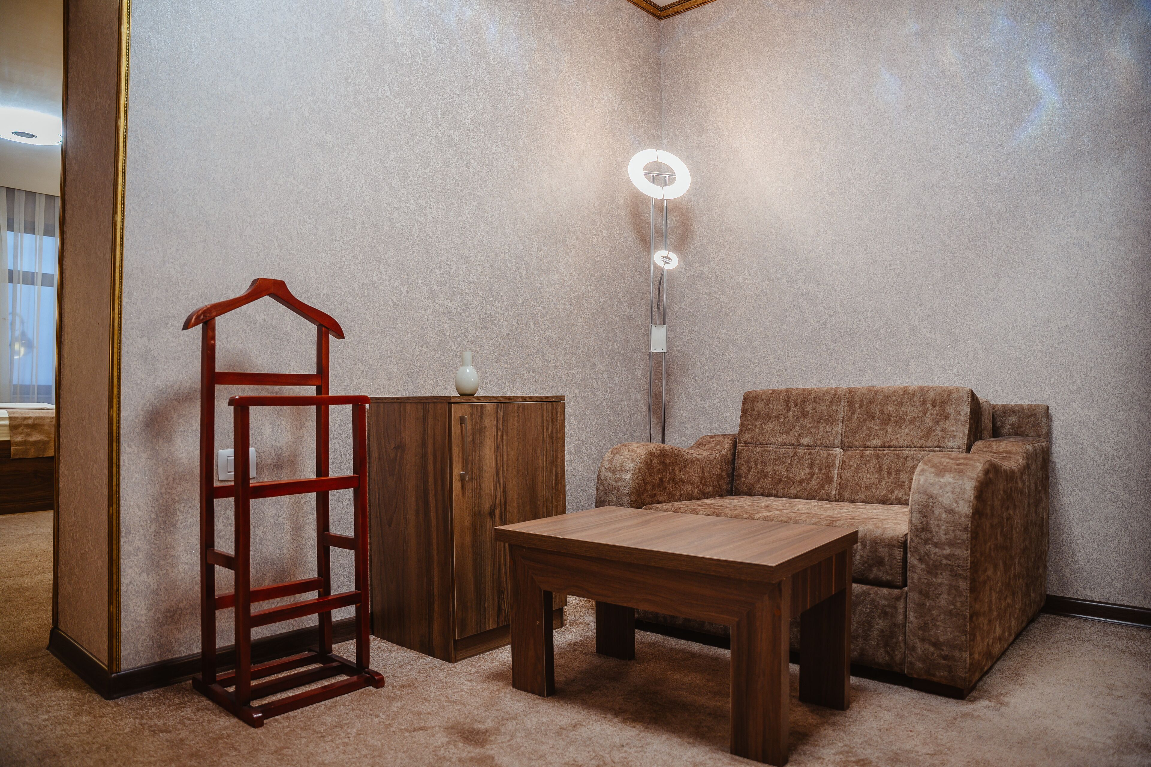 Une pièce comprenant une table en bois, un canapé marron, un meuble en bois et un luminaire fixé au mur.
