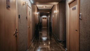 A hotel hallway with wooden doors, numbered room signs, and wall-mounted light fixtures. - Alison Hotel Baku (Baku)