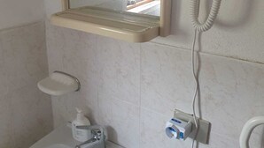 A bathroom with a toilet, sink, mirror, and a telephone mounted on the wall.