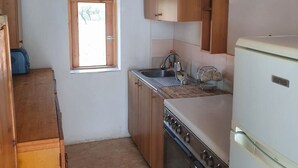 A compact kitchen with wooden cabinets, a built-in oven, a sink, and a window.