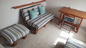 A small, cozy room with a single bed, a wooden table, and a bench.