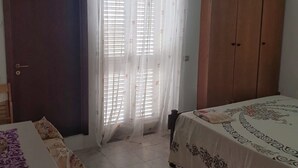 A bedroom with a bed, a wardrobe, a door, and a window with curtains.