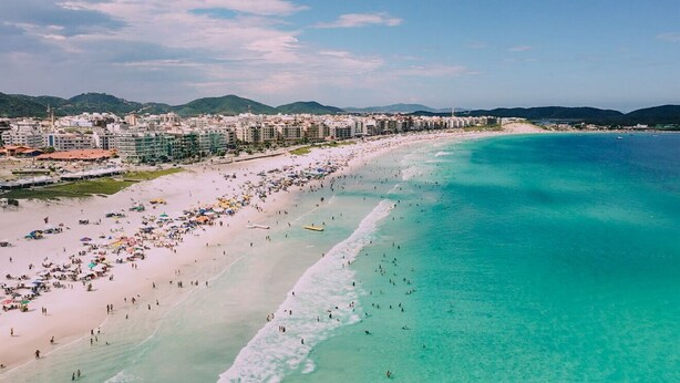 Un paisaje urbano costero con una playa extensa, aguas turquesas cristalinas y una zona densa con rascacielos.