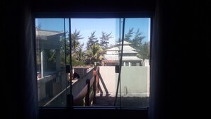 Vista a través de una ventana que muestra un edificio tradicional, palmeras y una estructura de concreto.