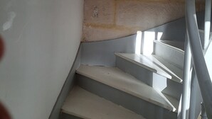 Eine Treppe mit weißen Stufen und einem Metallgeländer, die zu einer Ziegelwand führt.