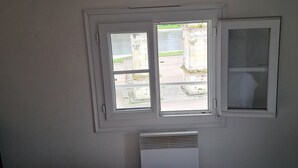 Ein Schlafzimmer mit einem Bett, zwei Fenstern und einer weißen Heizung.