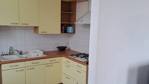 Eine Küche mit gelben Schränken, einer weißen Fliesenspiegel und einem Gasherd sowie einem Spülbecken.