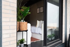A bedroom with a bed, a potted plant, and a window with a view.