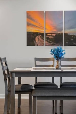Enjoy meals in this dining area with a wooden table and matching chairs, accompanied by a vase with fresh flowers and framed artworks.