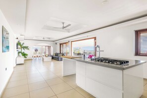 A spacious kitchen with a central island, large windows, and a view of the outdoors. - Exclusive 10p Villa: Seaview, Pool & Private Beach (Bandabou)