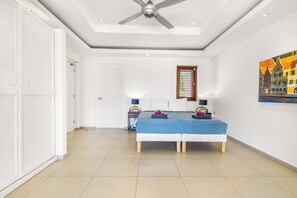 Ein Schlafzimmer mit einem Bett, Nachttischen, einem Deckenventilator, einem Fenster mit Jalousien und einem Gemälde an der Wand.