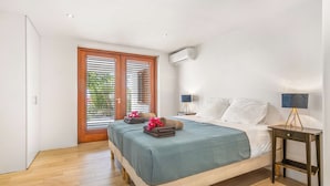 Une chambre à coucher avec un lit, des tables de chevet, une lampe et une fenêtre avec des stores.