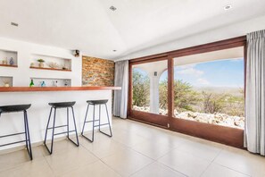 Eine moderne Küche mit Steinrückwand, einer Bar mit Barhocker und einem großen Schiebeglasfenster mit Blick auf die Wüste.