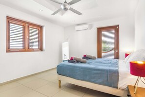 A bedroom with a bed, a ceiling fan, an air conditioning unit, and two windows with blinds. - Exclusive 10p Villa: Seaview, Pool & Private Beach (Bandabou)