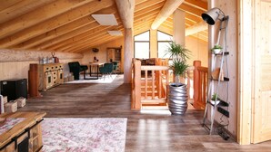 Een ruime loft met hoge plafonds, houten balken, een grote eethoek en een gezellige zithoek met een open haard.
